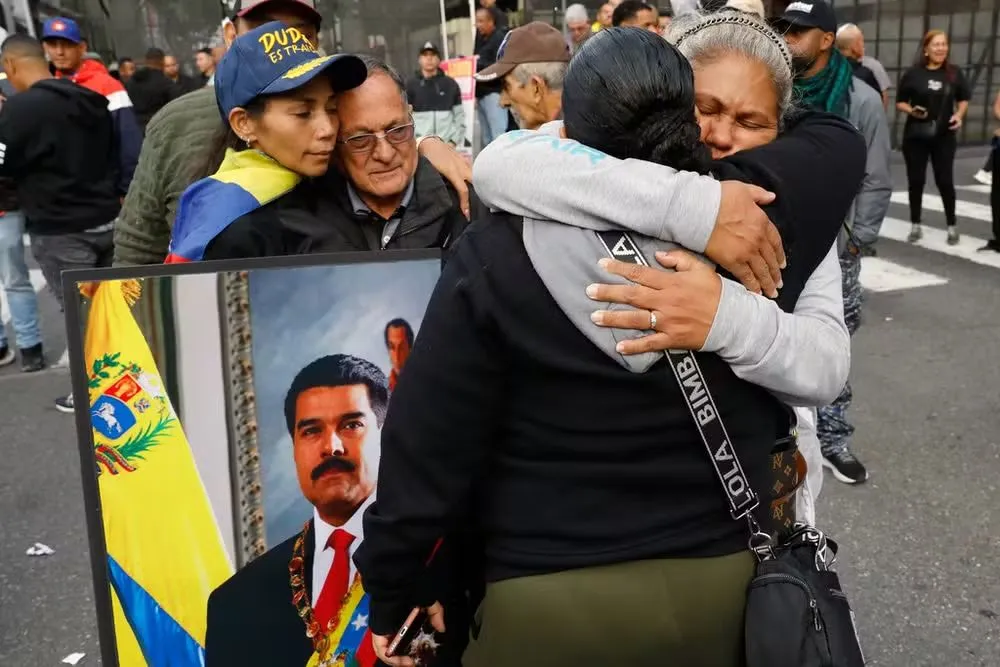 Apoiadores de Nicolás Maduro se abraçam durante ato de apoio após captura do presidente pelos EUA, em rua em Caracas em 3 de janeiro de 2025. — Foto: Matias Delacroix/ AP